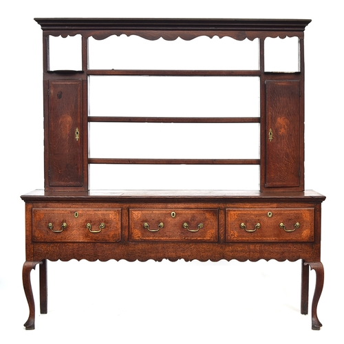 505 - A George II oak dresser, the rack with moulded pediment over three shelves flanked by cupboards, the... 