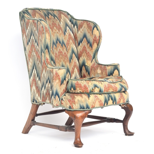 598 - A George I walnut framed wingback armchair, having outward scrolling arms, the cabriole front legs o... 