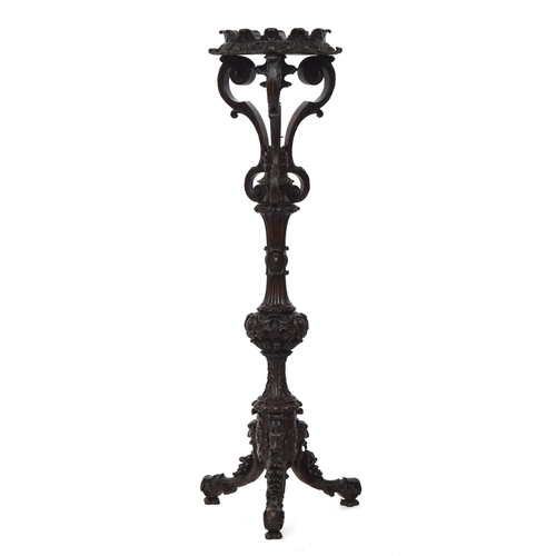 650 - A heavily carved torchere standing on three large carved supports, each topped by a grotesque mask, ... 