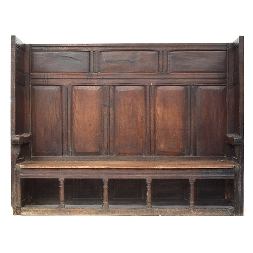 467 - An 18th century oak tavern settle, the panelled back and sides over a two plank pine seat, on four t... 