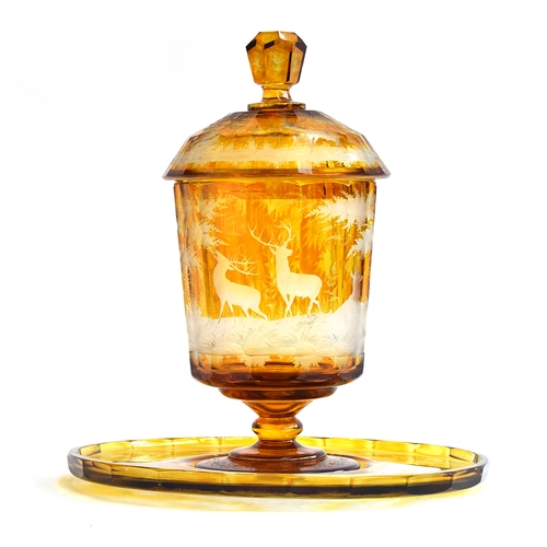 207 - A 19th century Bohemian amber glass footed punch bowl, cover and stand, engraved with deer in a wood... 