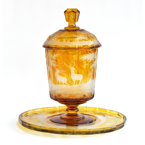 207 - A 19th century Bohemian amber glass footed punch bowl, cover and stand, engraved with deer in a wood... 