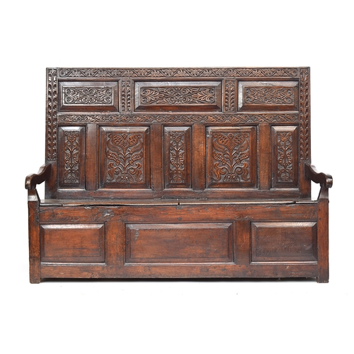 459 - A 17th century carved tavern settle, carved panelled back, downward sloping arms, hinged seats, thre... 