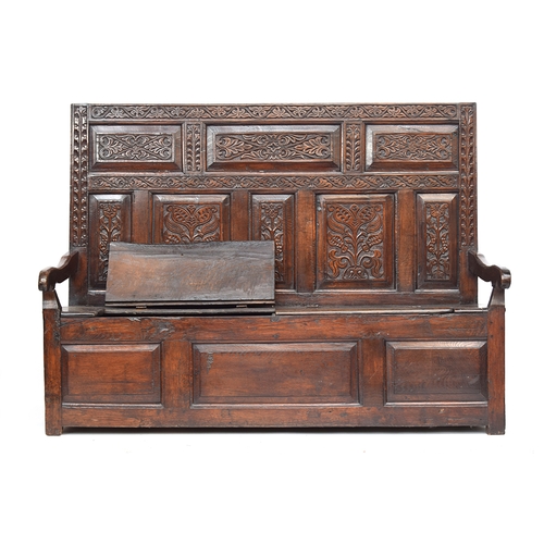 459 - A 17th century carved tavern settle, carved panelled back, downward sloping arms, hinged seats, thre... 