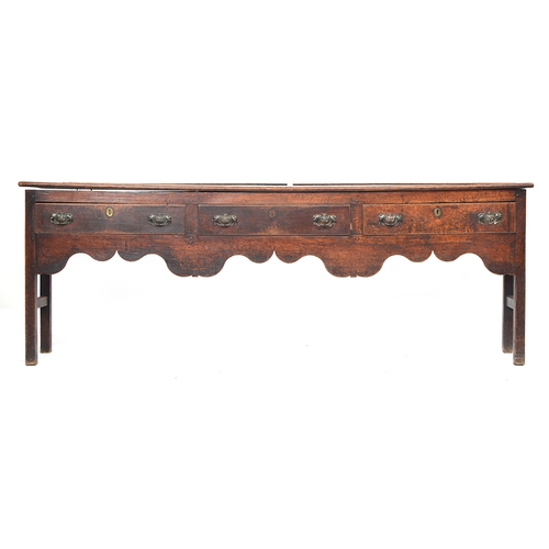 506 - An 18th century oak dresser base, three drawers over a shaped apron, on chamfered square section leg... 