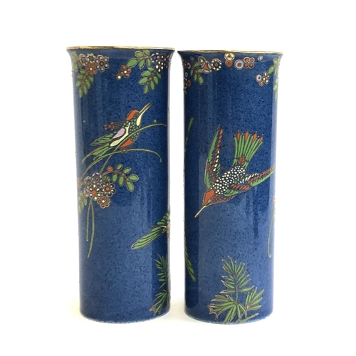 74 - A pair of Maling Art Deco cylindrical vases, with hummingbird pattern against a blue ground, marked ... 