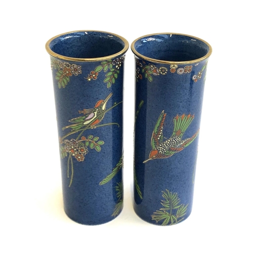 74 - A pair of Maling Art Deco cylindrical vases, with hummingbird pattern against a blue ground, marked ... 