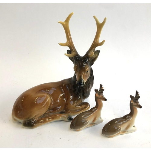 90 - A pair of Lomonosov recumbent deer figurines; together with an AA porcelain stag