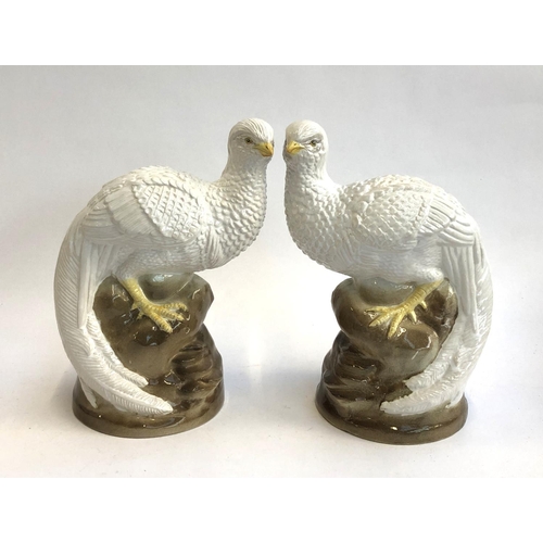 93 - A pair of continental glazed bird figures, each perched on a rocky outcrop, 26cmH