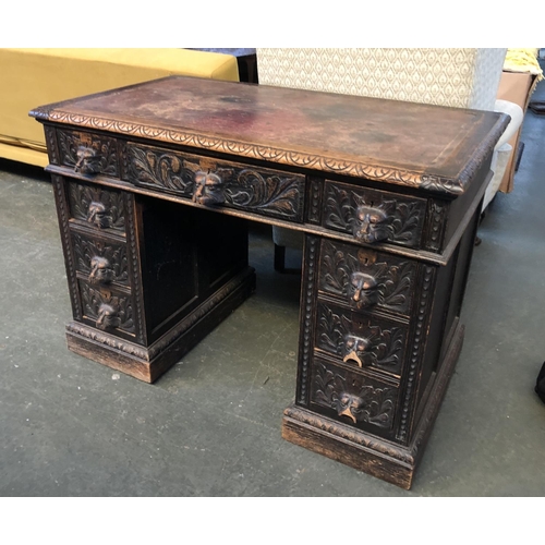 682 - An oak kneehole desk, the drawers carved with lion mask handles (some af), on plinth base, 106x61x75... 