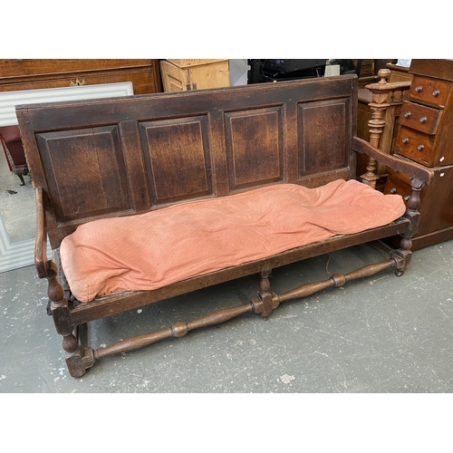 698 - An 18th century and later four panel oak settle, with cushion seat, turned supports and later stretc... 