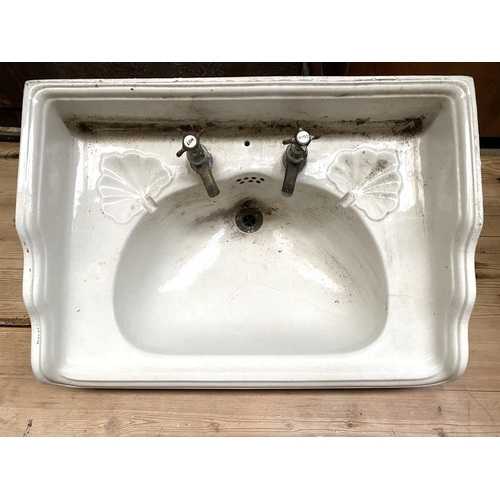 662 - An early 20th century wash basin, with brass taps and plughole, with cast metal wall mount (af), 66x... 