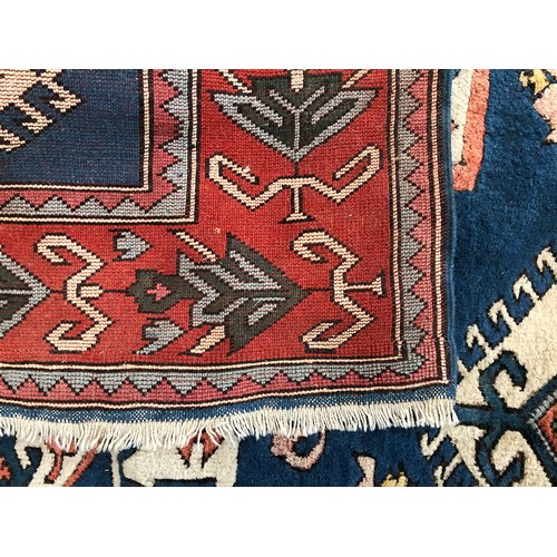 538 - A large wool Persian style rug, central serrated lozenge on a blue ground, 255x185cm