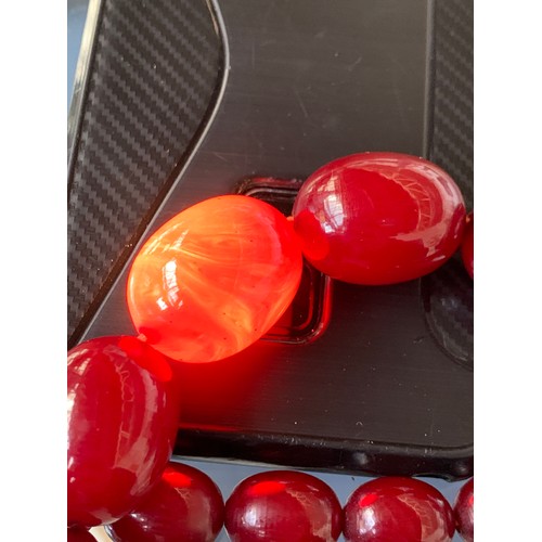 11 - A cherry amber bakelite graduated bead necklace, the largest bead 2.5cm long, total length 89cm uncl... 