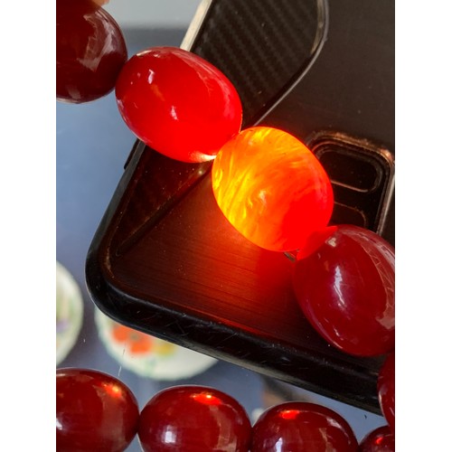 11 - A cherry amber bakelite graduated bead necklace, the largest bead 2.5cm long, total length 89cm uncl... 