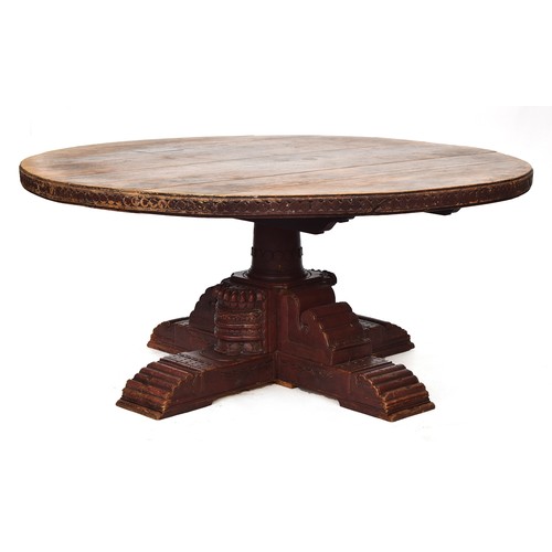 590 - A substantial Indian hardwood dining table, 19th century, the circular top with a carved edge, on a ... 