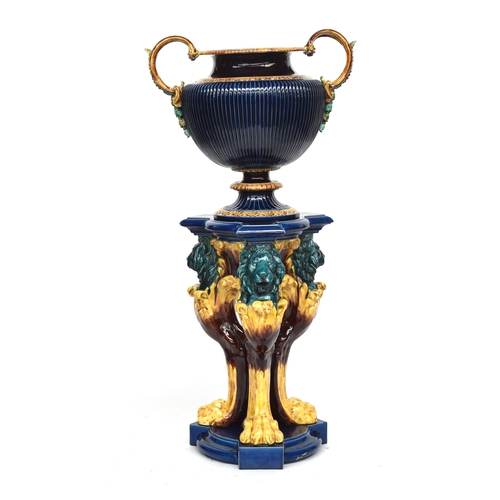 199 - A massive Sarreguemines majolica urn, with twin handles and gadrooned body, supported by triform ped... 