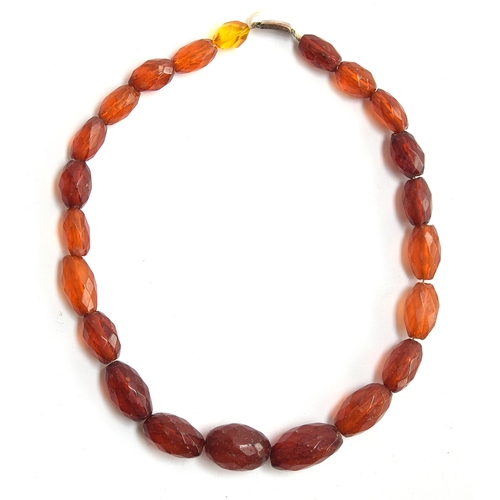 40 - A faceted amber bead necklace, with a 9ct gold clasp, the largest bead 2.7cm long (one bead yellow g... 