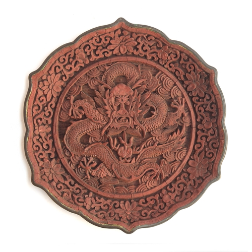 118 - A Chinese cinnabar lacquer lotus shaped dish depicting a dragon and a flaming pearl, surrounded by i... 