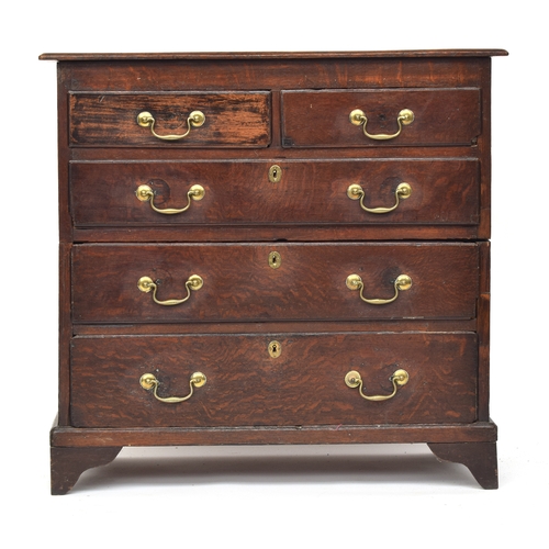 473 - An early 18th century oak chest of two short over three graduating drawers, on bracket feet, cut in ... 