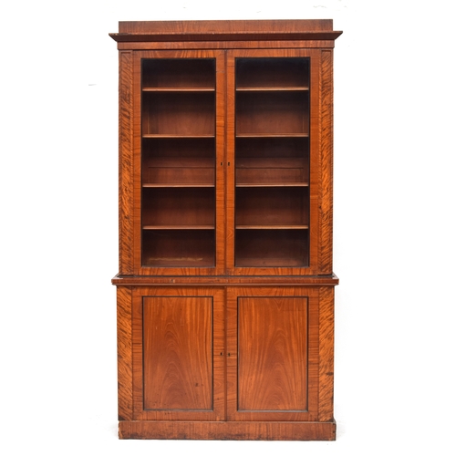 515 - A 19th century satin mahogany library bookcase, the pediment top over two glazed doors opening to fo... 