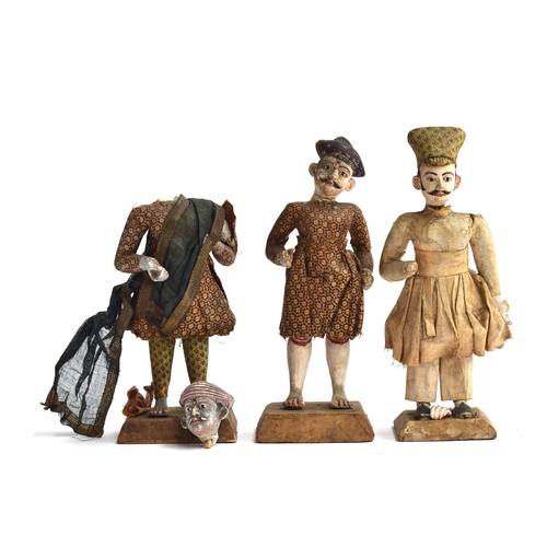 173 - Three late 19th century Indian clay figures of men, in material clothing, some losses, each on a woo... 