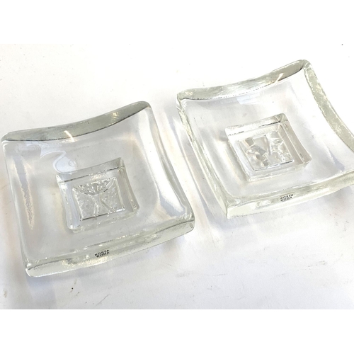 152 - Two Kosta Boda square glass dishes, each 10cm square, together with two glass candle stick holders, ... 