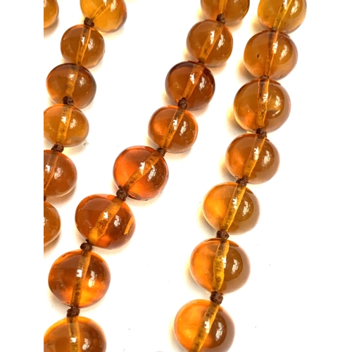 55 - A long string of amber beads, knotted, each bead approx. 1.4cmW, one bead cracked, approx. 95g, 50cm... 