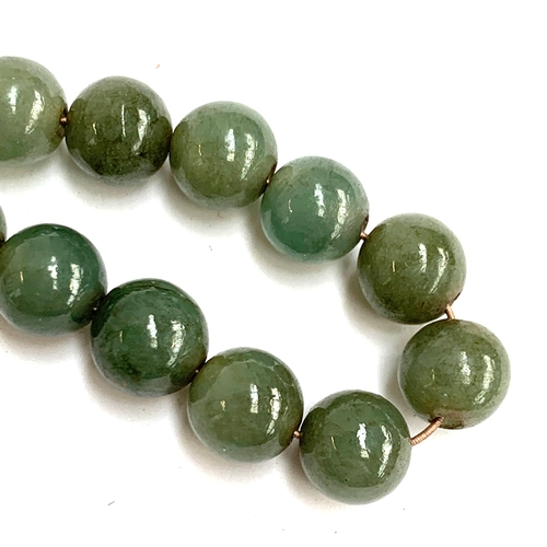 54A - A Chinese jade bead necklace, the beads approx. 0.7cmD, in need of restringing, with a white metal b... 