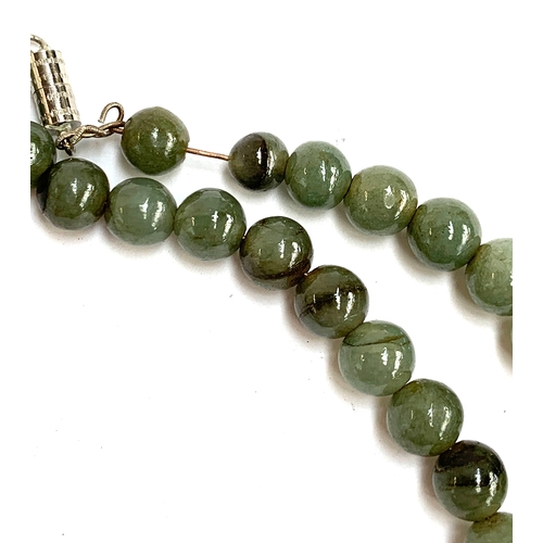 54A - A Chinese jade bead necklace, the beads approx. 0.7cmD, in need of restringing, with a white metal b... 