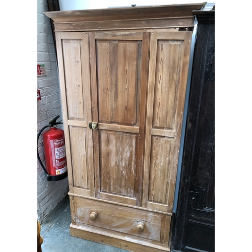 1045 - A 20th century pine hanging wardrobe, panelled door over a single drawer, 96x47x185cmH