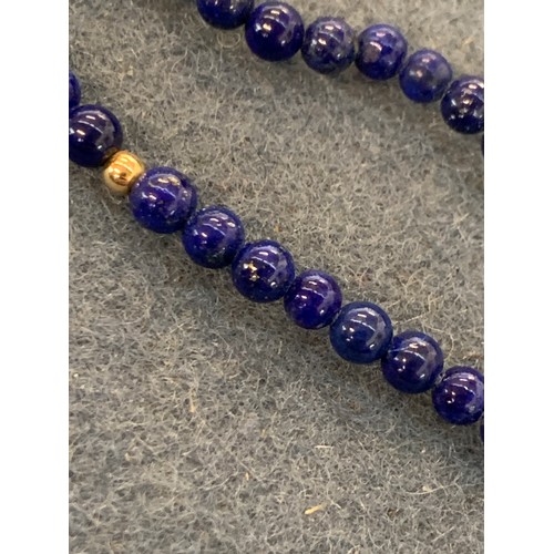 27 - A long lapis and gold (tests as 14ct or higher) bead necklace, the lapis beads approx. 3mm in diamet... 