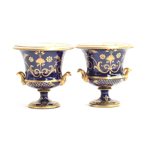 214 - A pair of 19th century twin handled porcelain urns, each with hand painted floral panel on a cobalt ... 