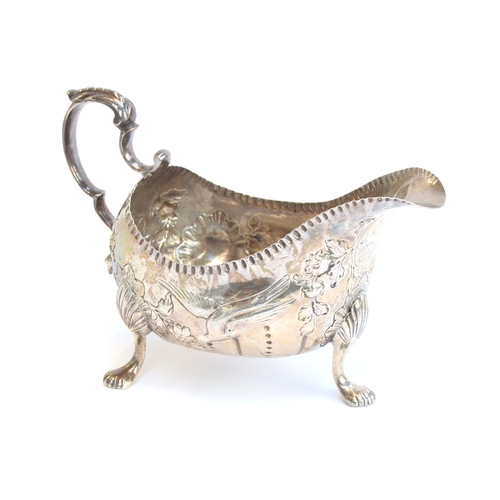 92 - A George III Irish sterling silver sauce boat on three feet, leaf capped handle, chased with fabulou... 