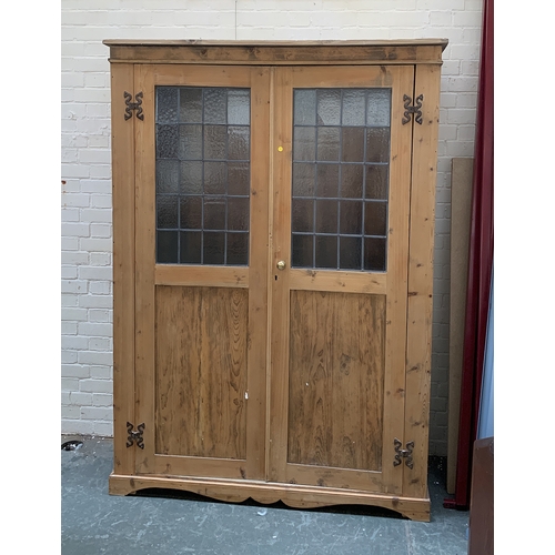 1010 - A large pine cupboard, the doors with lead glazed upper section, opening to an interior with hanging... 