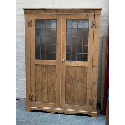 1010 - A large pine cupboard, the doors with lead glazed upper section, opening to an interior with hanging... 