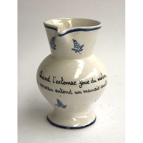 169 - A French faience jug, hand painted with blue floral motifs and the motto 'Quand l'estomac joue du vi... 