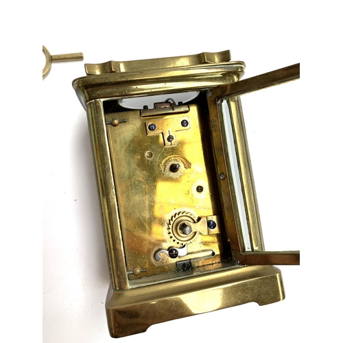 94 - A brass carriage clock with bevelled glass and enamel dial with Roman numerals, 11cmH, with key