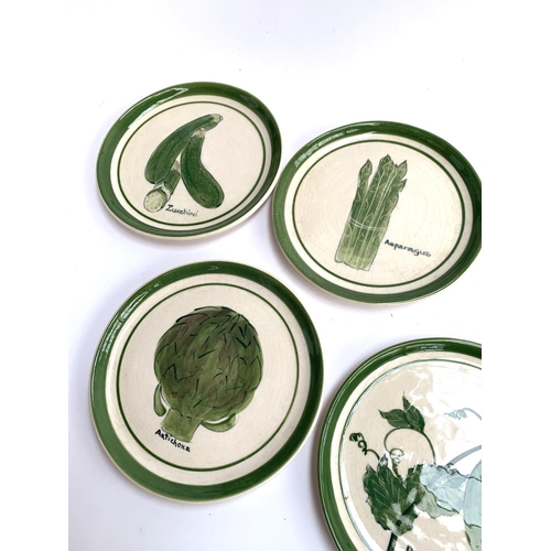 423 - A set of eight hand painted plates decorated with various green vegetables including asparagus, bean... 