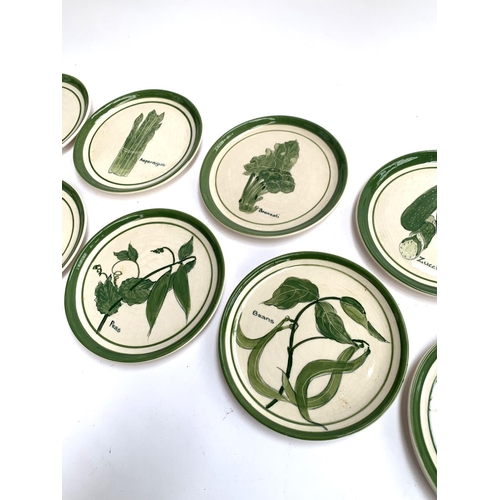 423 - A set of eight hand painted plates decorated with various green vegetables including asparagus, bean... 