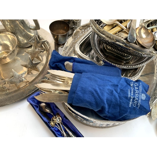 85 - A mixed lot of plated items to include star napkin rings, cutlery in a Garrard wrap, serving trays e... 