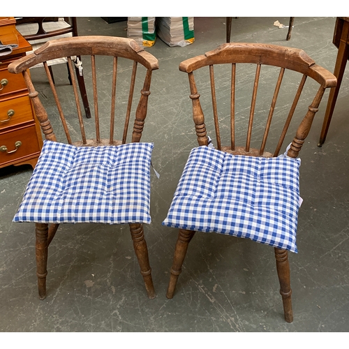 986 - A pair of stick back kitchen chairs, three part rail over saddled elm seats, on ring turned legs and... 