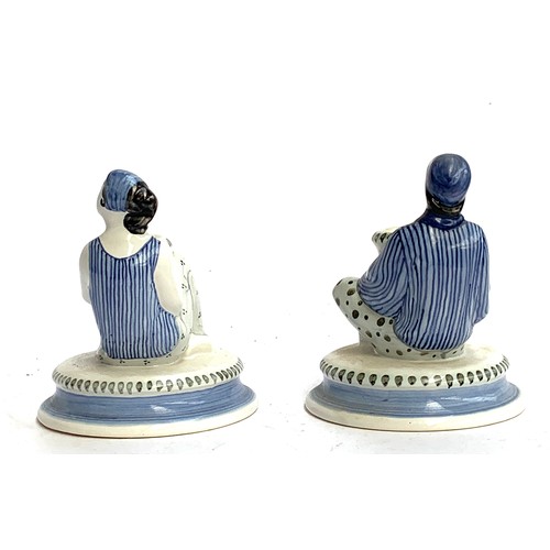 106 - A pair of Rye Pottery hand painted figural candlesticks in the form of a seated man and women in str... 