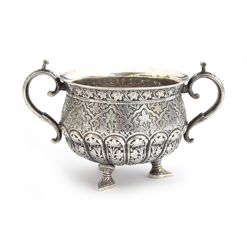 105 - An Indian silver twin handled sugar bowl, the half gadrooned body allover chased with foliate design... 