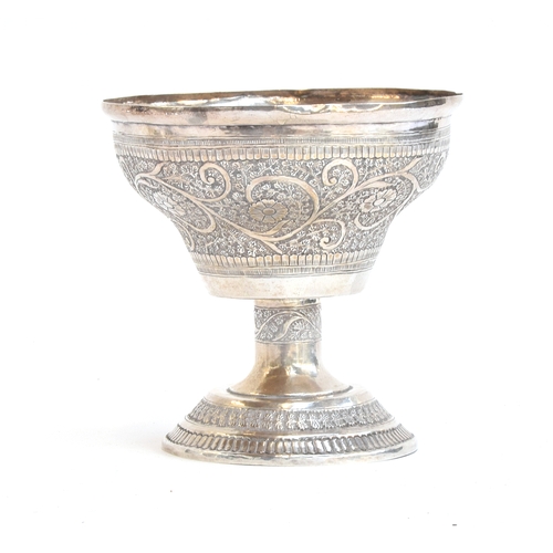 114 - An Eastern white metal goblet, chased with scrolling foliate detail, on a chased stem and spreading ... 