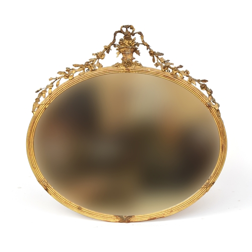 764 - A 19th century Italian gilt gesso oval mirror, with urn, ribbon and floral swag cresting, over a ree... 