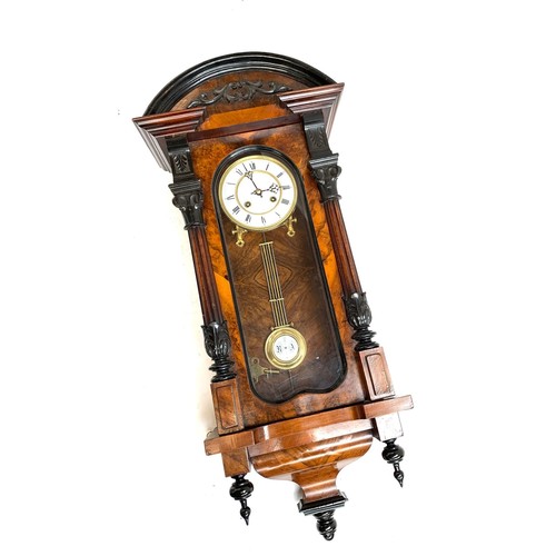 61 - An early 20th century mahogany cased wall clock, with enamel dial and pendulum, 62cmL