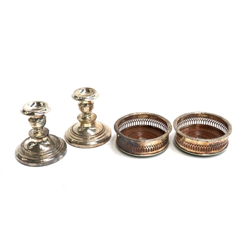 68 - A pair of pierced silver plated wine coasters, 13cmD; together with a pair of plated candlesticks