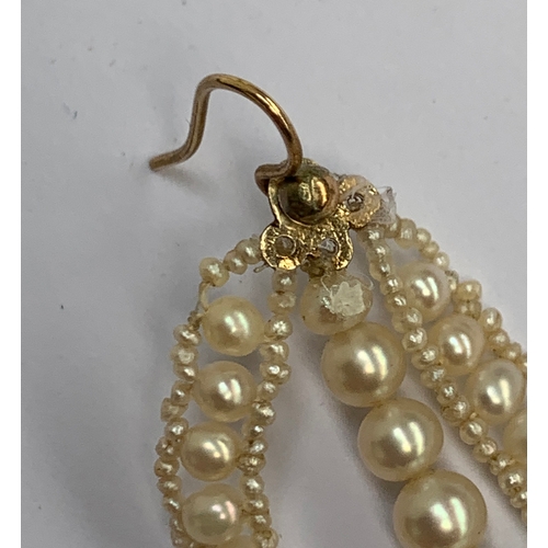 12 - A pair of delicate pearl earrings, designed as a central string of seven pearls framed within a tear... 