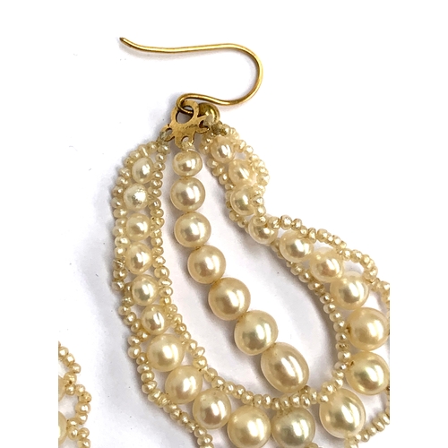 12 - A pair of delicate pearl earrings, designed as a central string of seven pearls framed within a tear... 